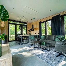 Modernes Wohnzimmer eines freistehenden Hauses in IJhorst, Nordwest-Overijssel, mit groen Fenstern und Blick auf die grne Natur.