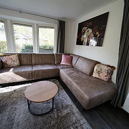 Gezellige woonkamer in Vrijstaande woning in IJhorst, Overijssel, met comfortabele bank en uitzicht op de groene omgeving.