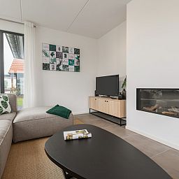 Gezellige woonkamer in Watervilla 8, een vakantiehuis in Ossenzijl, Noordwest Overijssel, met moderne inrichting en sfeervolle haard.