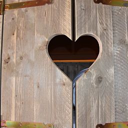 Holztuer mit herzfoermigem Fenster in Cottage in Vinkeveen, Ferienhaus in Vinkeveen, Utrecht Nord, umgeben von rustikalem Charme.