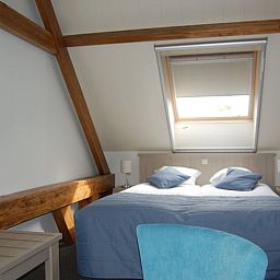 Lichte slaapkamer in Vakantiehuisje in Vreeland, Utrecht met houten balken en groot dakraam.