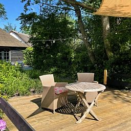 Charmante zithoek op houten veranda van Huisje in Tienhoven, vakantieaccommodatie in Tienhoven, Utrecht.