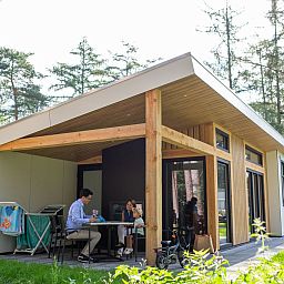 Geniet van de rust op het terras van Bungalow Molenstein, een vakantiehuis in Doorn, Utrechtse Heuvelrug, omgeven door groene natuur.