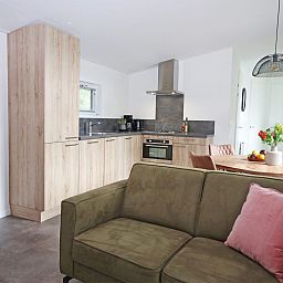 Gezellige woonkamer en keuken in Bungalow Molenstein, Doorn, Utrechtse Heuvelrug. Perfect vakantiehuis voor een ontspannen verblijf in de natuur.
