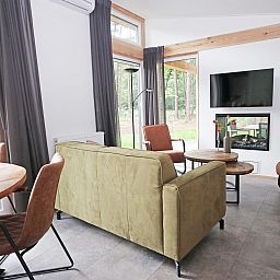Gezellige woonkamer in Bungalow Molenstein, Doorn, Utrechtse Heuvelrug, met uitzicht op de natuur en moderne inrichting.