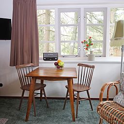 Eethoek in Bungalow Ficus, Doorn, Utrechtse Heuvelrug, met houten tafel en uitzicht op bosrijke omgeving.