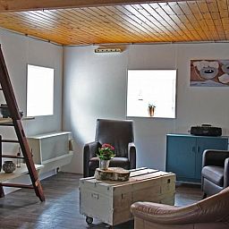 Gemuetliches Wohnzimmer von Huisje in Achterveld, einem Ferienhaus in der Utrechter Huegelkette, Utrecht, mit komfortabler Sitzecke und Holzdecke.