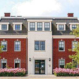 Charmanter Aussenbereich des Apartments Ganuenta in Colijnsplaat, Nord-Beveland, mit roten Ziegeln und bluehenden Blumen.
