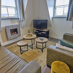 Cozy living room of Sauna Zee 27H in Colijnsplaat, North Beveland, with comfortable sofas and a modern fireplace.