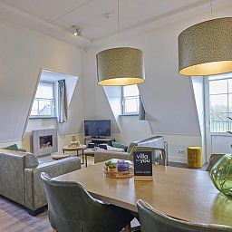 Cozy living room of Sauna Zee 27H vacation home in Colijnsplaat, North Beveland, with modern decor and lots of natural light.