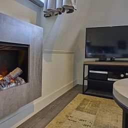 Cozy living room of Sauna Zee 27H in Colijnsplaat, North Beveland, with modern fireplace and flat-screen TV in the vacation home.