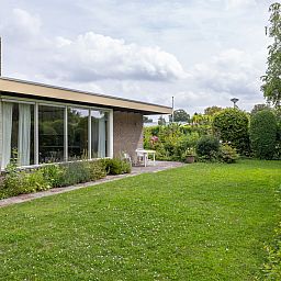 Blick in den Garten des Ferienhauses ZE167 in Kamperland, umgeben von Gruen und Blumen.