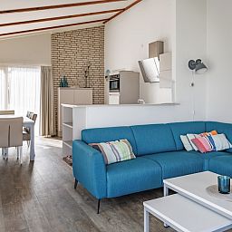 Modernes Wohnzimmer des BA Comfort Bungalows in Kamperland, Zeeland, mit geraeumiger Sitzecke und offener Kueche fuer einen entspannten Urlaub.