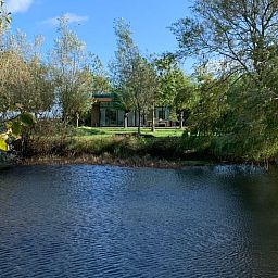 Ferienhaus in Kamperland mit Blick auf einen ruhigen Teich, umgeben von Natur in Nord-Beveland, Zeeland.