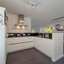 Moderne Kueche in der Villa R10B, einem Ferienhaus in Kamperland, Noord-Beveland, Zeeland, mit Blick auf die gruene Umgebung.