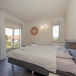 Attraktives Schlafzimmer in der Villa R10B, Ferienhaus in Kamperland, Zeeland, mit heller Einrichtung und Blick auf die gruene Umgebung.