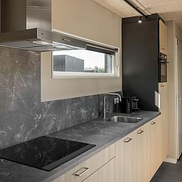Moderne keuken in Lodge 4, een vakantiehuis in Kamperland, Noord-Beveland, Zeeland, met strakke inrichting en uitzicht op de omgeving.