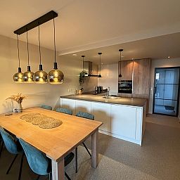Moderne keuken en eetruimte in Havenweg 24, een vakantiehuis in Kamperland, Noord-Beveland, Zeeland met stijlvolle lampen en houten tafel.