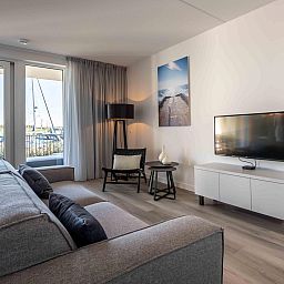 Moderne zithoek in vakantiehuis Harbour Loft 1E, Noord-Beveland, met uitzicht op zeilboten.