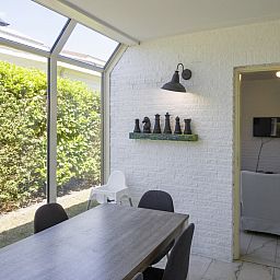 Modern kitchen in bungalow RJV, Kamperland, Zeeland with rustic wooden table top and view of green surroundings.