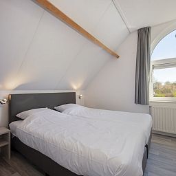 Helles und geraeumiges Schlafzimmer in der Villa R6A, einem Ferienhaus in Kamperland, Noord-Beveland, Zeeland, mit Blick auf die gruene Umgebung.
