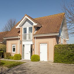 Modernes Badezimmer in der Villa R6A, einem Ferienhaus in Kamperland, Nord-Beveland, Zeeland, mit hellen Fliesen und einem bunten Duschvorhang.