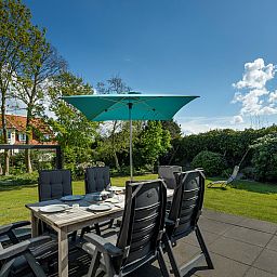 Terrace of Holiday home Schouwse Duin 35 in Burgh-Haamstede with garden table and parasol for summer days in Zeeland.