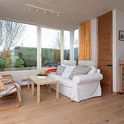 Bright living room in Holiday Home Horizon by the Sea, Renesse, with comfortable seating and views of the garden.