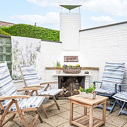 Sunny terrace with deck chairs and fireplace at Holiday home Horizon by the Sea, Renesse, ideal for relaxation.