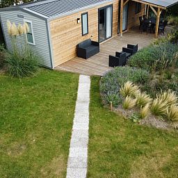 Verseputshofje chalet in Renesse, Schouwen-Duiveland, Zeeland met een uitnodigende veranda en weelderige tuinomgeving.