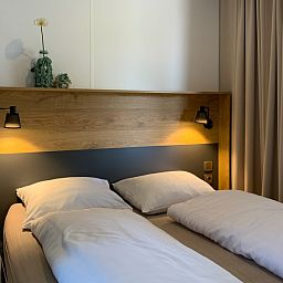 Gezellige slaapkamer in Verseputshofje chalet, Renesse, met comfortabel tweepersoonsbed en sfeervolle verlichting, Zeeland vakantiehuis.