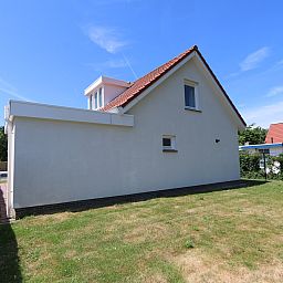 Side view of Holiday home Horizon 95 in Zeeland, surrounded by a green garden for privacy and tranquility.