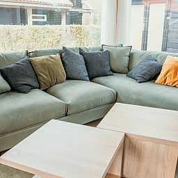 Cozy sitting area in vacation home Zonnedorp 14 Mon Repos in Renesse with green sofa and cushions