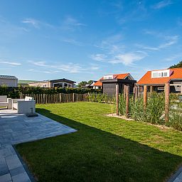 Zonnig terras bij Vakantiehuis Zonnedorp 28 in Renesse, omgeven door natuur.