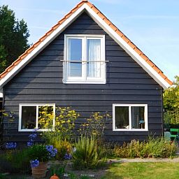 Aussenansicht des Ferienhauses in Dreischor, ein attraktives Ferienhaus in Schouwen-Duiveland, Zeeland, mit einem schoenen Garten und blauem Himmel.