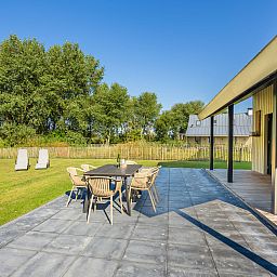 Ruim terras van Vakantiehuis Oesterdam Resort in Tholen, Zeeland met uitzicht op de natuur.