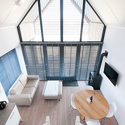 Modernes Interieur des Ferienhauses Oesterdam Resort in Tholen, Zeeland, mit hohen Fenstern.