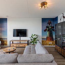 Stijlvolle woonkamer in Appartement in Scherpenisse, Tholen, Zeeland met moderne inrichting en kunst aan de muur.