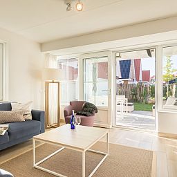 Lichte woonkamer van Banckert Luxe Outdoor 4 vakantiehuis in Koudekerke, Walcheren, met uitzicht op terras en tuin.
