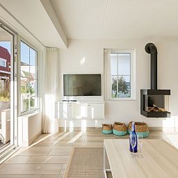 Lichte woonkamer van Banckert Luxe Outdoor 4 vakantiehuis in Koudekerke, Walcheren, Zeeland met moderne inrichting en uitzicht op terras.
