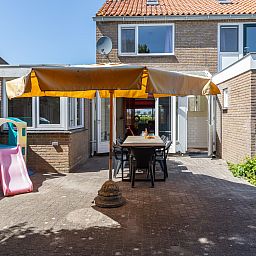 Geraeumige Terrasse des Ferienhauses ZE142 in Koudekerke, Walcheren mit grossem Sonnenschirm und Sitzgelegenheit.