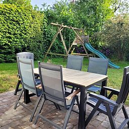Tuin met eettafel en speeltoestel bij VZ2330 Vakantiehuis in Oostkapelle, Walcheren, Zeeland.