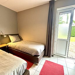 Bedroom with two beds in Apartment Boszicht 1, Oostkapelle, Walcheren, with access to the garden.
