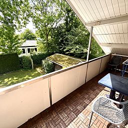 Balkon van Appartement Boszicht 4 in Oostkapelle, Walcheren, Zeeland met uitzicht op groene tuin.