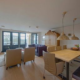 Eetkamer en zitgedeelte van Champagne Wellness 6 appartement in Domburg met uitzicht op de natuur.