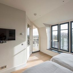 Slaapkamer in Champagne Wellness 6 in Domburg, Zeeland met grote ramen en uitzicht op de omgeving.