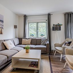 Gemuetliches Wohnzimmer des MK7 Comfort Bungalows in Domburg, Walcheren, Zeeland mit bequemer Sitzecke und Gartenblick.