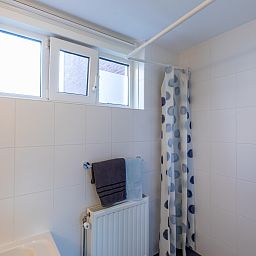 Stijlvolle badkamer in vakantiehuis ZE1594 in Domburg, Walcheren, Zeeland met een ligbad en witte tegels.