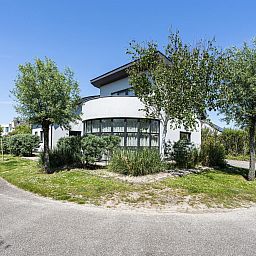 Seitenansicht der Luxus-Ferienvilla VZ908 in Vlissingen, umgeben von Baeumen in Walcheren, Zeeland.