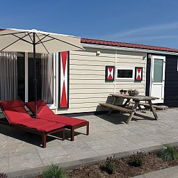 Terrasse von VZ816 Chalet in Veere, Serooskerke, Walcheren, mit Picknicktisch und Sonnenschirm.